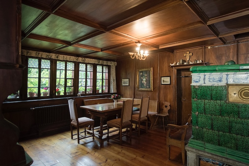 Die Stube mit Tisch und Kachelofen…